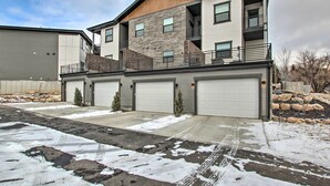 A modern multi-story residential building with a garage entrance, a stone facade, and a balcony. - Modern Mountain Escape Near Slopes, Lakes & Trails (Eden)