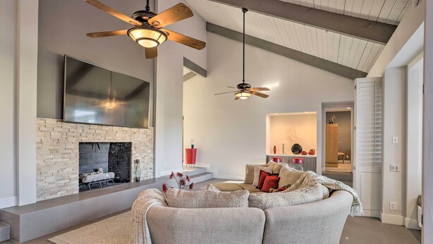 A modern living room with a fireplace, a large sofa, and a ceiling fan. - Sleek Rancho Mirage Villa: Patio, Pool, Golf! (Rancho Mirage)