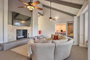 A modern living room with a fireplace, a large sofa, and a ceiling fan. - Sleek Rancho Mirage Villa: Patio, Pool, Golf! (Rancho Mirage)