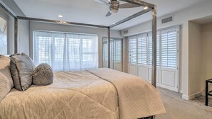 A bedroom with a four-poster bed, large windows with blinds, and a ceiling fan. - Sleek Rancho Mirage Villa: Patio, Pool, Golf! (Rancho Mirage)