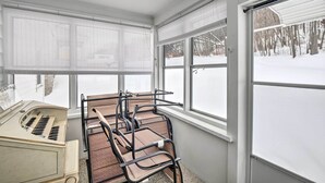 Una habitación con un piano, una ventana con persianas y vista a un paisaje nevado.