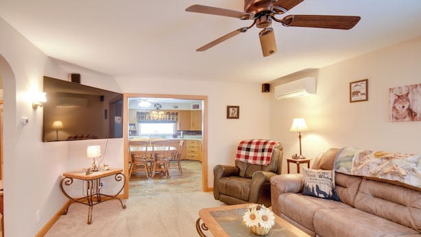Una sala de estar con ventilador de techo, un sofá, una mesa de centro y una zona de comedor al fondo.