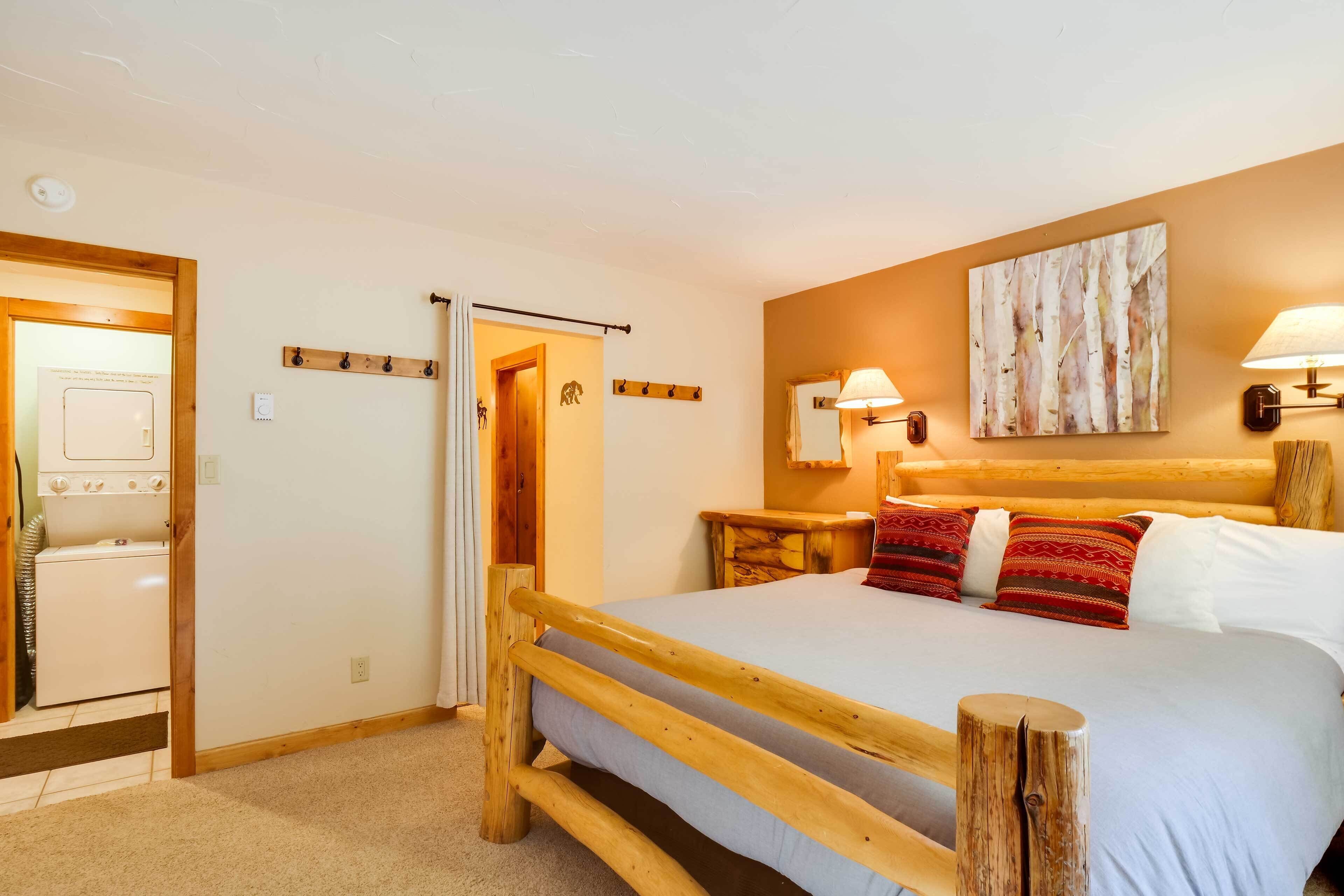 A bedroom with a wooden bed, a nightstand, a wall-mounted lamp, and a painting.