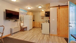 A compact kitchen with wooden cabinets, a built-in microwave, a refrigerator, and a flat-screen TV mounted on the wall. - Private Duck Creek Apartment Near Entertainment! (Duck Creek Village)