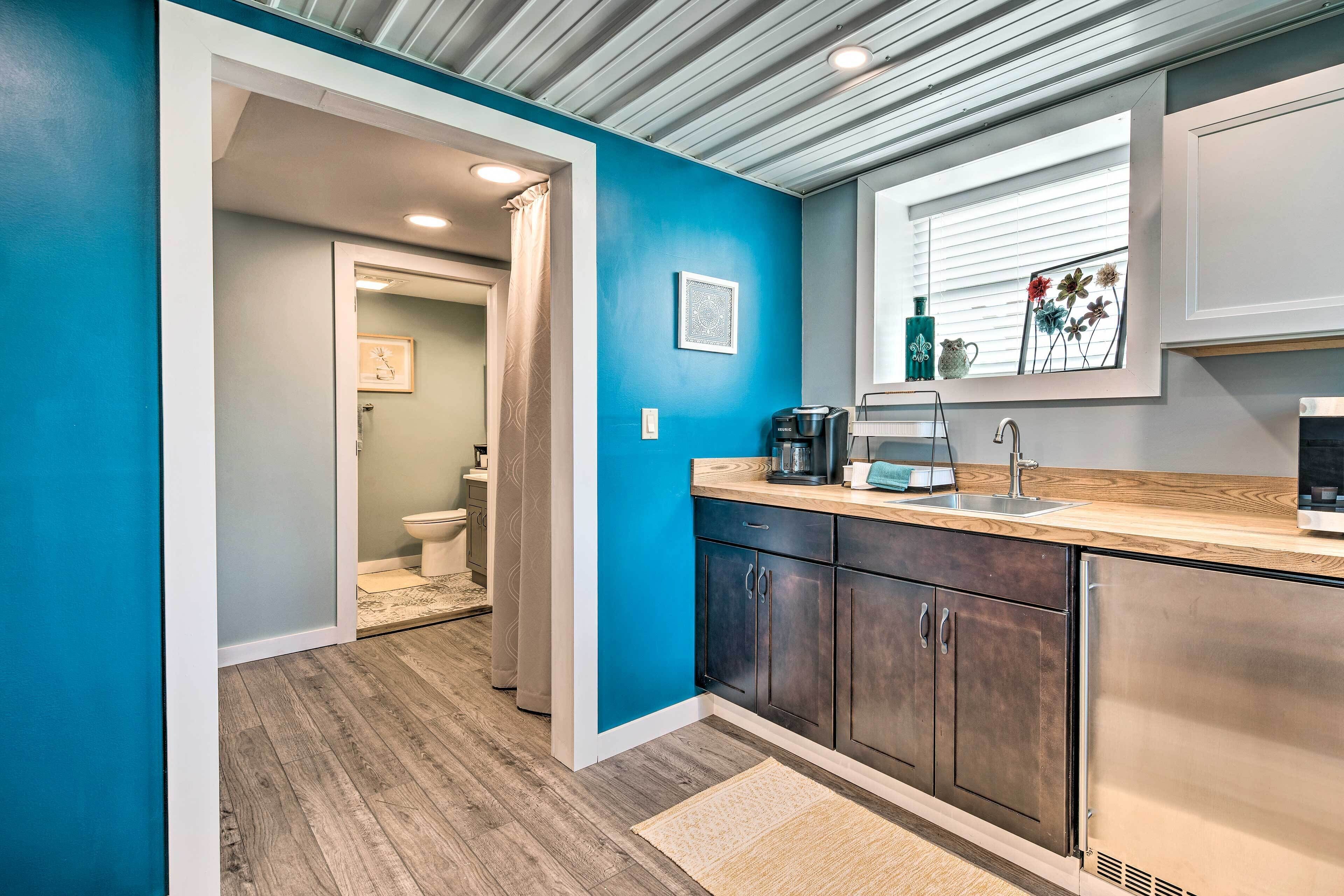A modern kitchen with a blue accent wall, stainless steel appliances, and a wooden countertop.