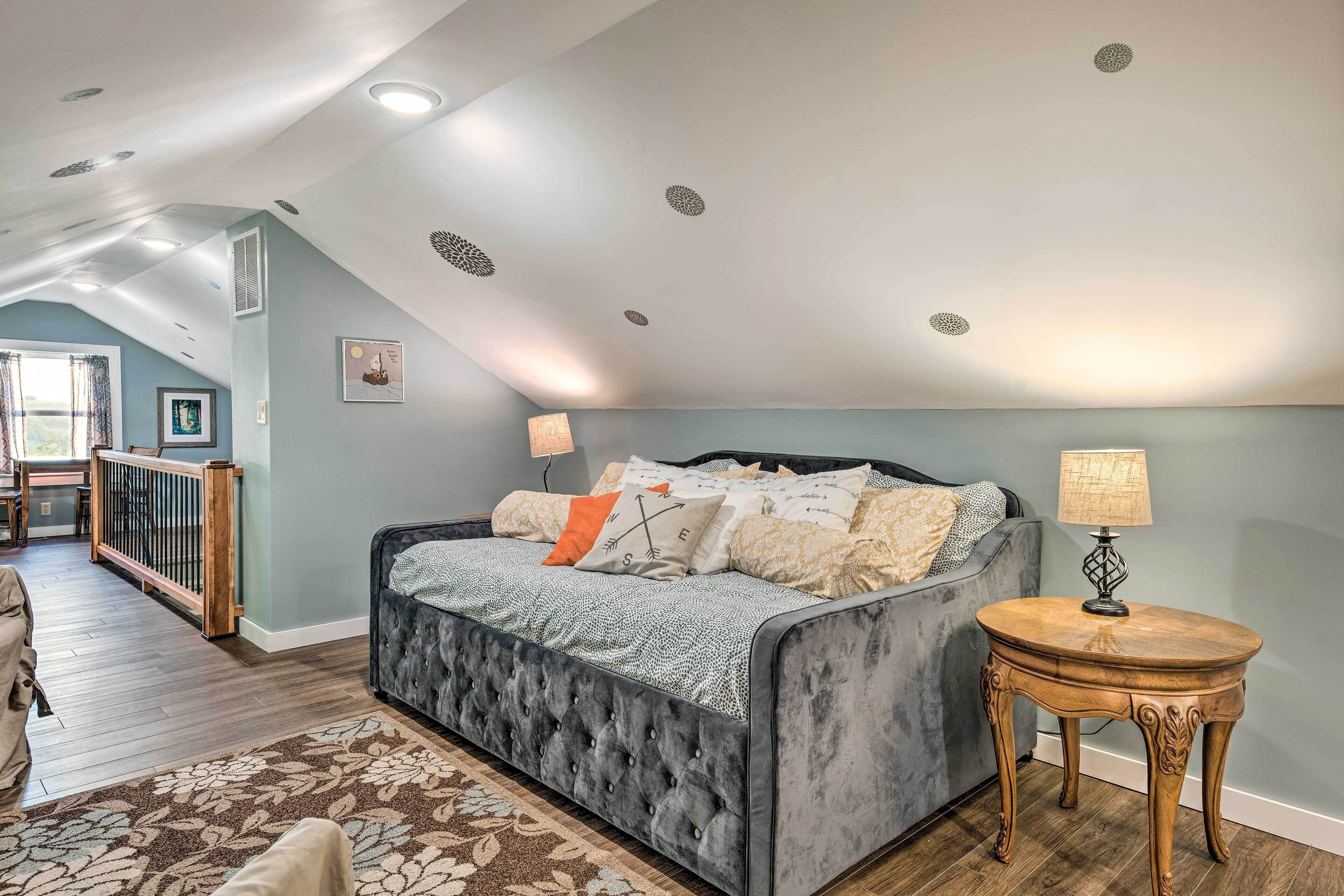 A bedroom with a tufted headboard bed, a round wooden side table, and a view of the balcony.