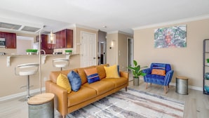 Een moderne woonkamer met een bruine leren bank, een blauwe fauteuil en een kamerkleed met een patroon.