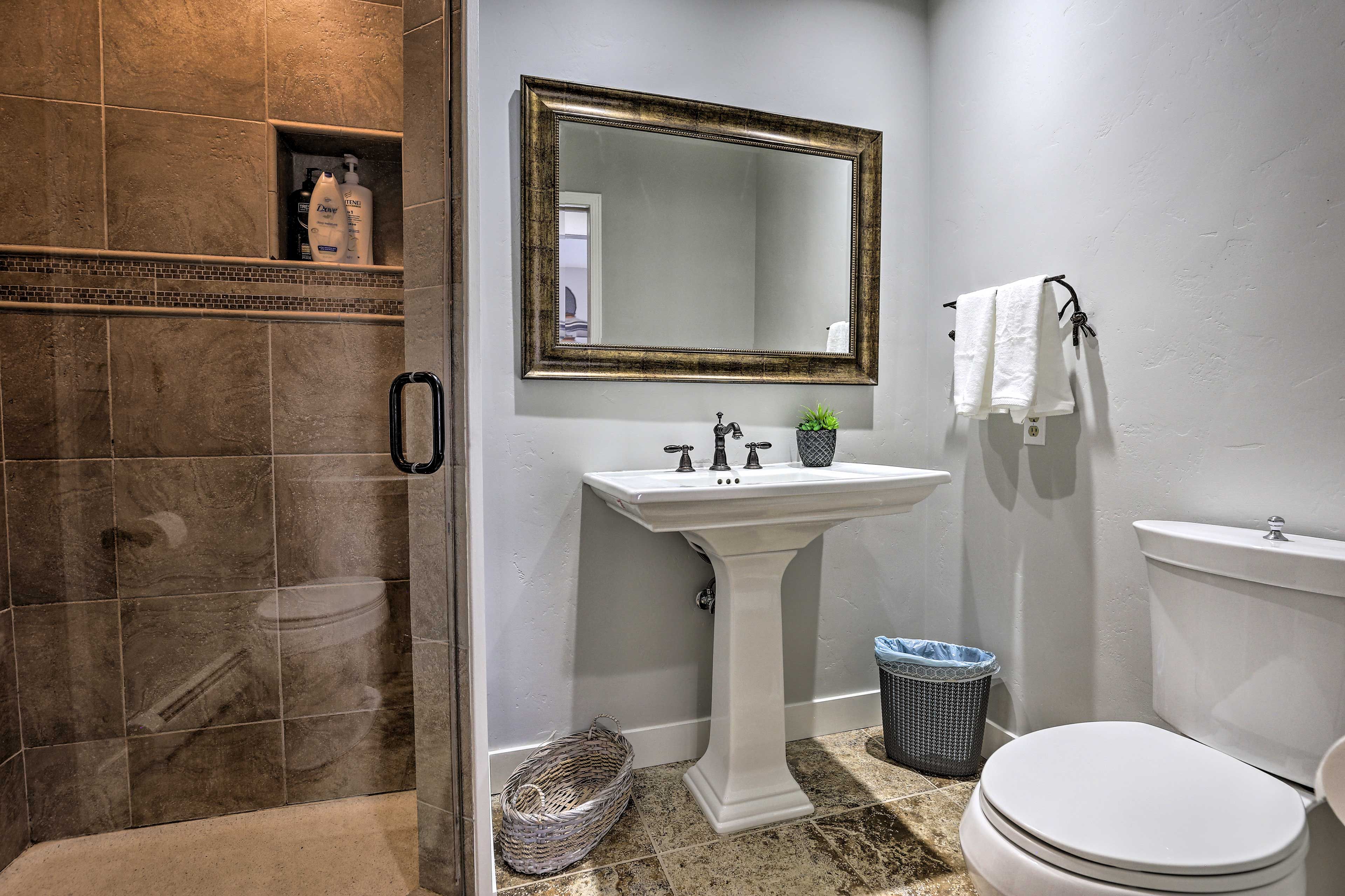 A bathroom with a shower, sink, toilet, and a large mirror.
