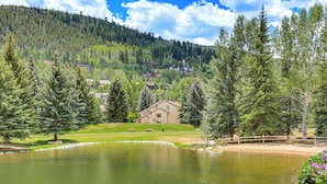 A lake surrounded by trees and houses, with a wooden fence and a bench. - Snowy Avon Nights Near Vail & Beaver Creek (Avon)