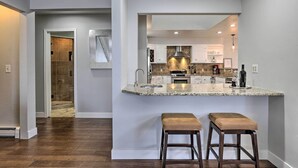 Una cocina moderna con encimera de granito, electrodomésticos de acero inoxidable y dos taburetes de bar.