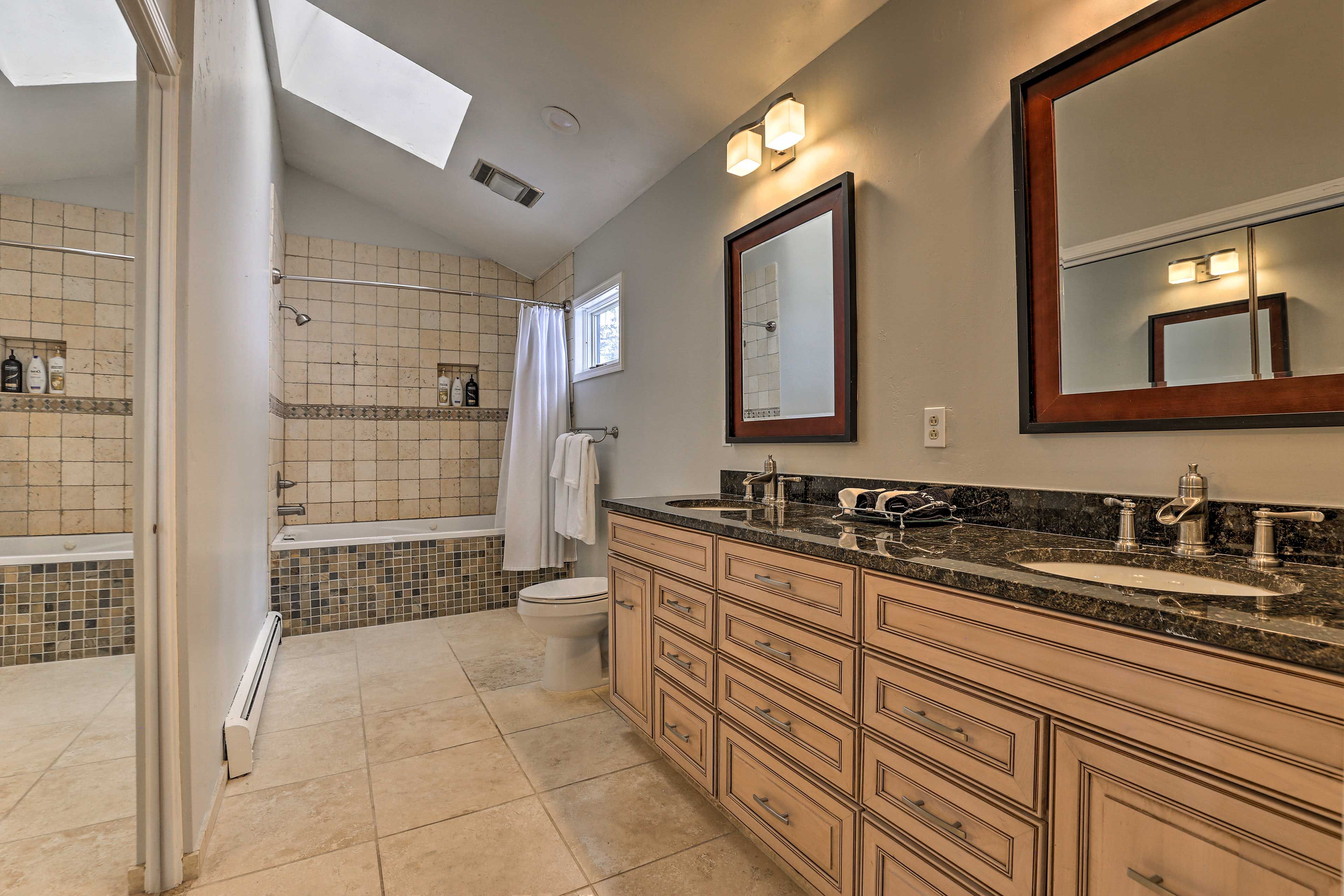 A modern bathroom with a large vanity, a bathtub, and a shower.