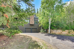 A two-story house with a stone chimney, a garage, and a stone wall. - Avon Duplex w/ Hot Tub: Ski Vail & Beaver Creek! (Avon)