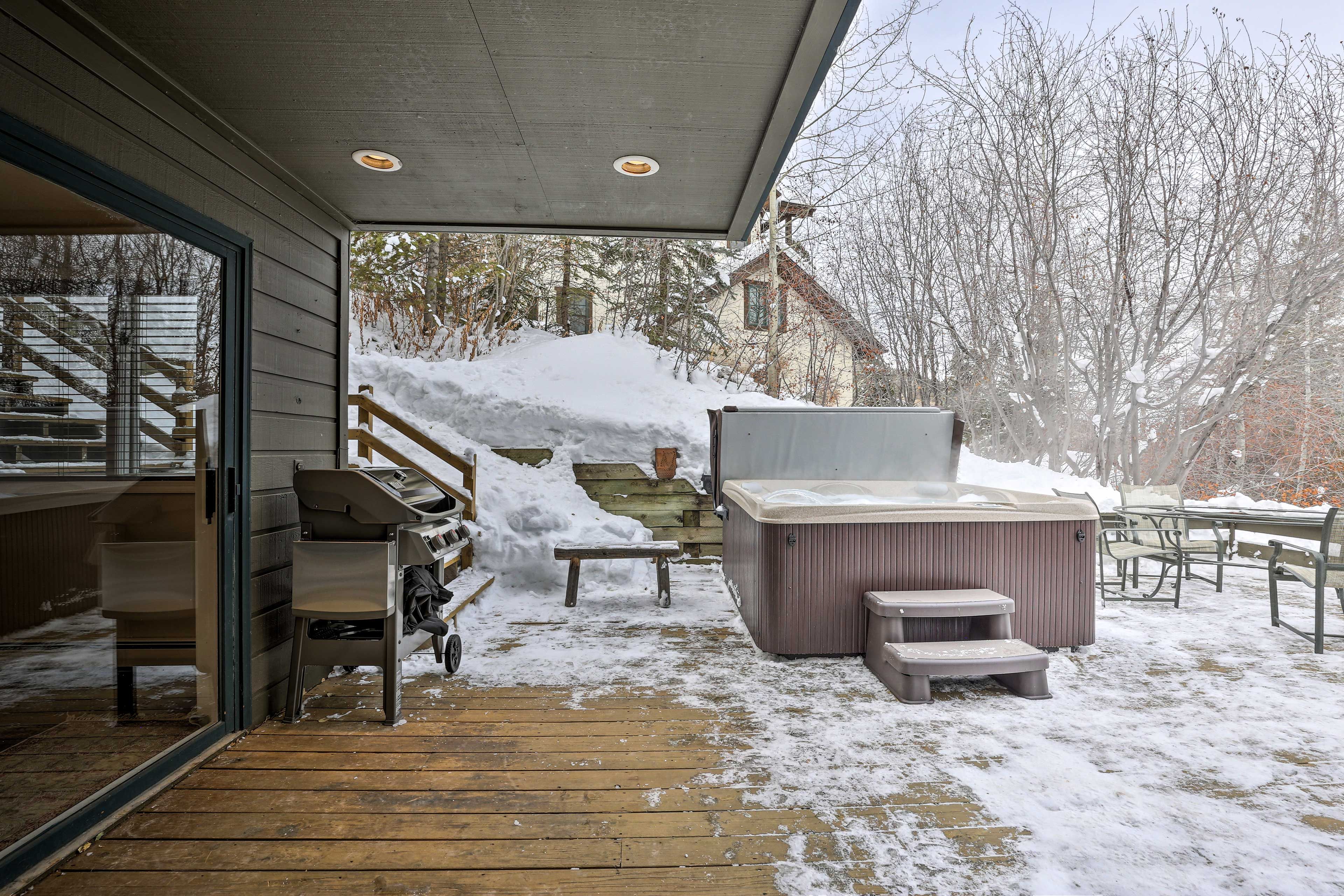 A covered outdoor area with a hot tub, wooden steps, and a bench.