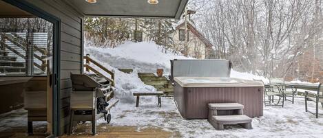 A covered outdoor area with a hot tub, wooden steps, and a bench.