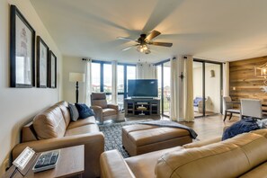 A spacious living room with a sofa, ottoman, and a television.
