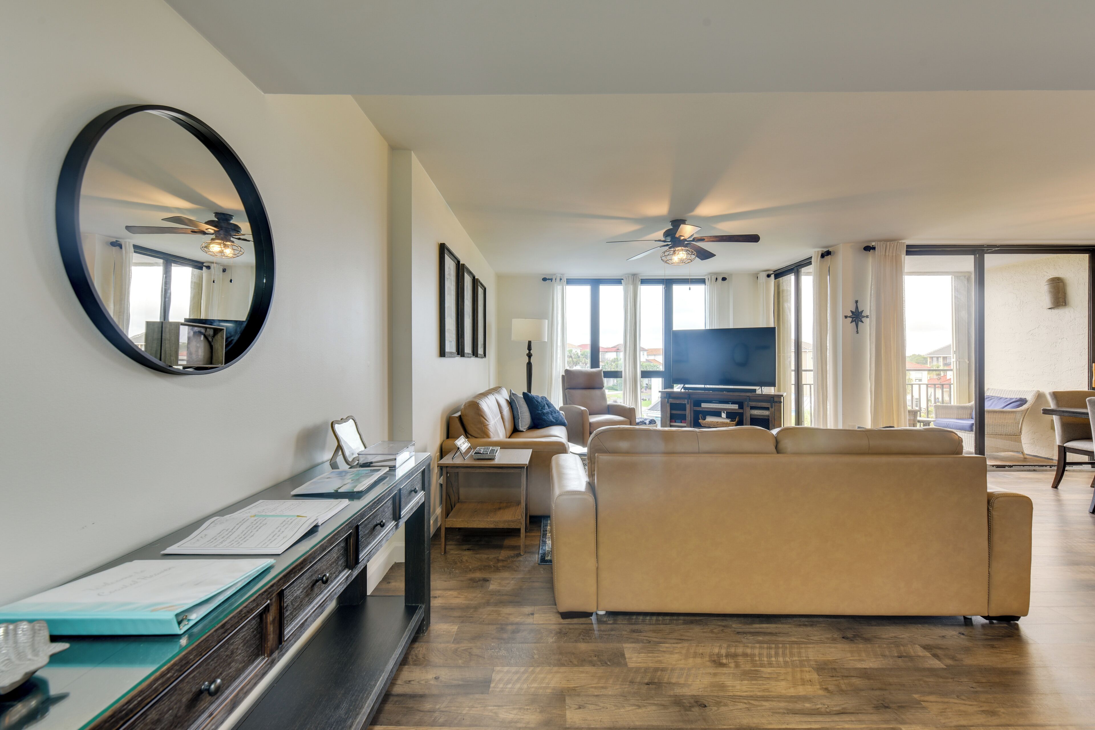 A living room with a sofa, a coffee table, a TV, and a ceiling fan.