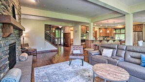 A spacious living area with a stone fireplace, a large sofa, and a coffee table. - Modern Alpine Home on Prospector Golf Course! (Cle Elum)