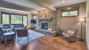 A modern living room with a stone fireplace, a sofa, a chair, and a lamp. - Modern Alpine Home on Prospector Golf Course! (Cle Elum)
