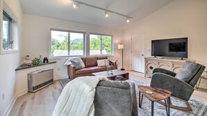 Ein Wohnzimmer mit einer Couch, einem Sessel, einem Couchtisch, einem Fernseher und einer Heizung.