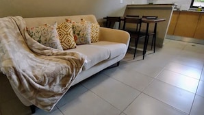 Sala de estar con sofá, una mesa de centro y una cocina al fondo.