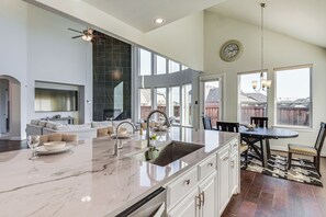Uma cozinha espaçosa com uma ilha grande, eletrodomésticos modernos e um espaço de jantar com lustre.