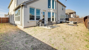 Ein zweistöckiges Haus mit überdachter Terrasse, einem eingezäunten Garten und einem sichtbaren Grill.