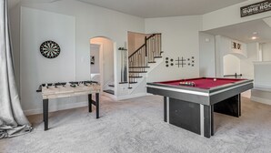 Ein Raum mit einer Fußballtable, einem Billardtisch und einer Dartscheibe.