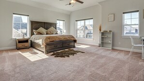 Ein Schlafzimmer mit einem großen Bett, einem Deckenventilator und mehreren Fenstern.