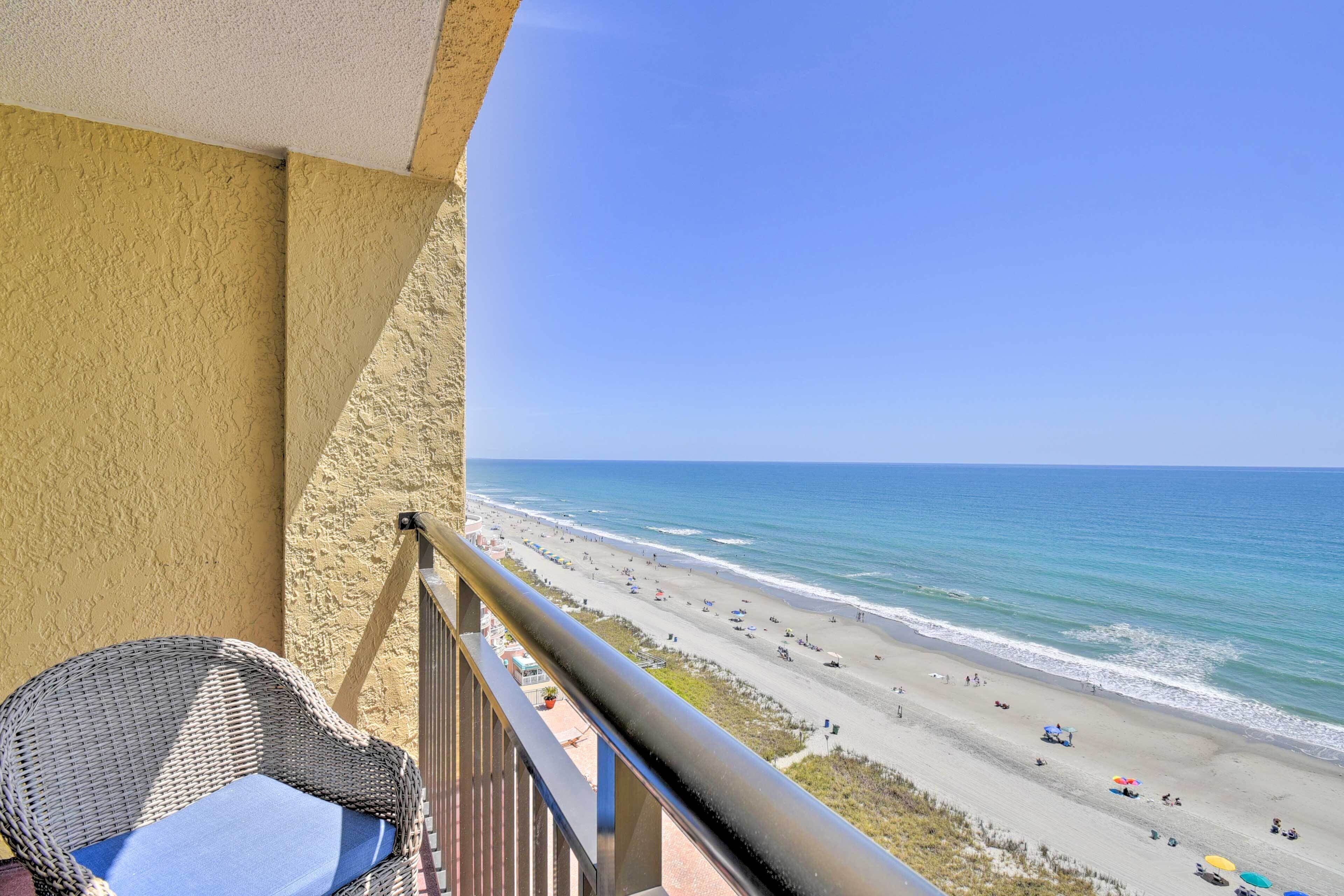 A balcony with a wicker chair and a view of a beach.