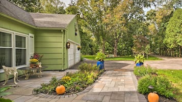 Une maison verte dotée d’un patio, de plantes en pot et d’un chemin menant à une pelouse.