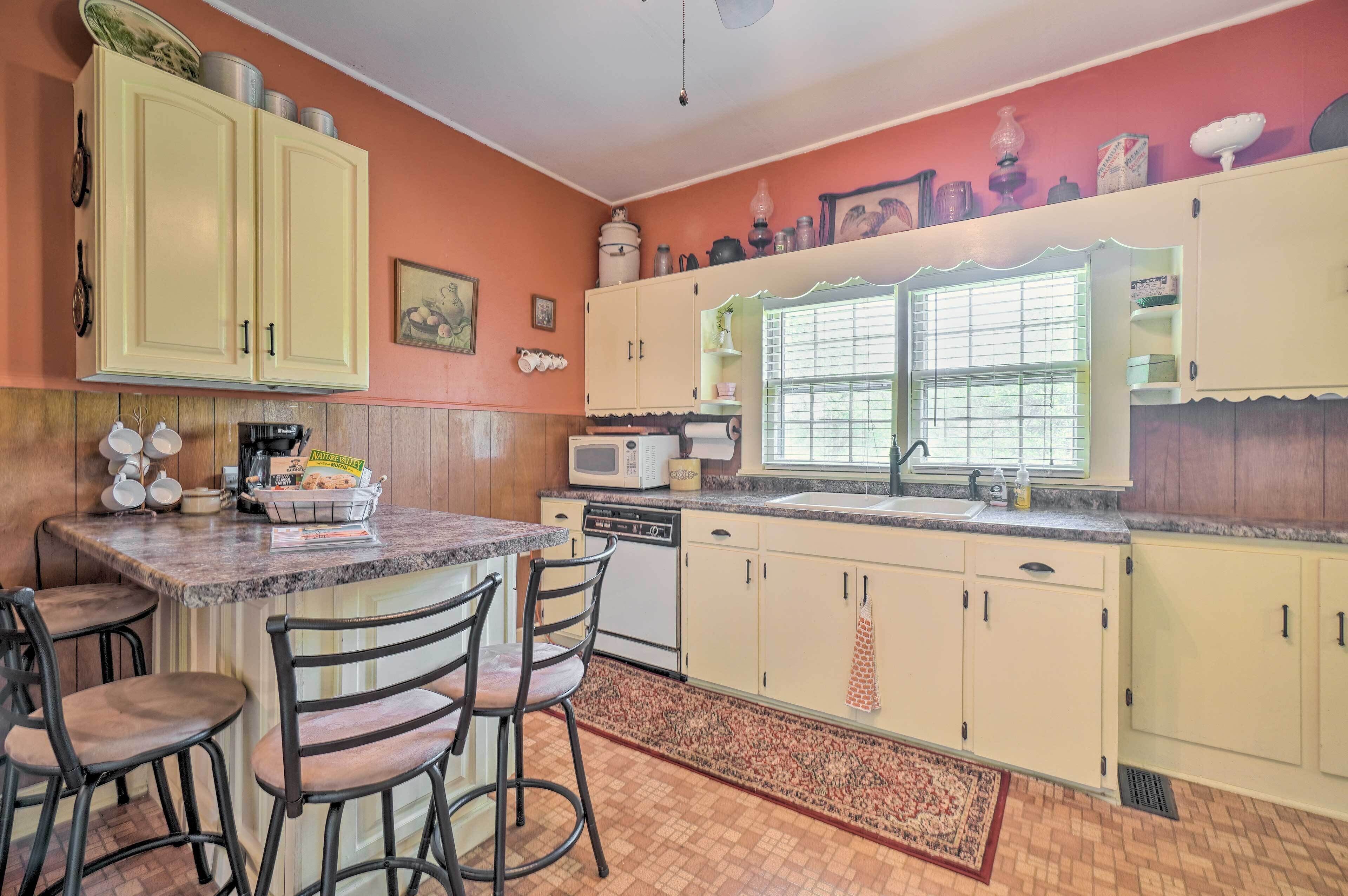 A kitchen with wooden cabinets, a microwave, a sink, and a window with blinds.