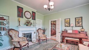 A traditional living room with a fireplace, two ornate chairs, a piano, and a bookshelf. - Historic Sparta Home Near Waterfalls & Hikes! (Sparta)