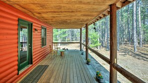 Een houten chalet met een overdekte veranda, een deur en ramen.