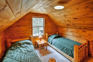 Un chalet confortable avec deux lits en bois, une petite table et une fenêtre donnant sur le paysage extérieur.