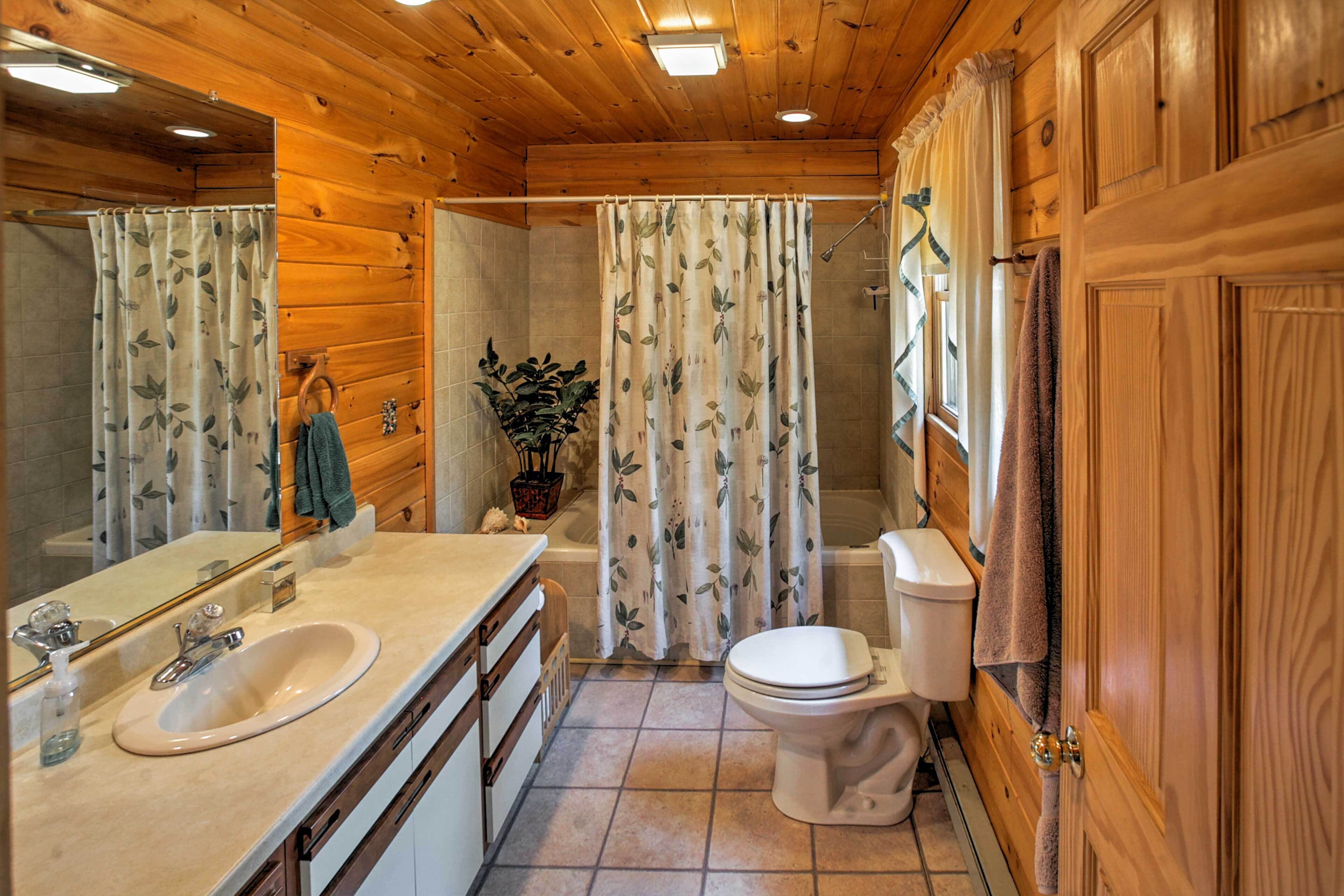 Une salle de bain rustique, aménagée dans une cabane en bois, avec un lavabo, des toilettes et une douche.