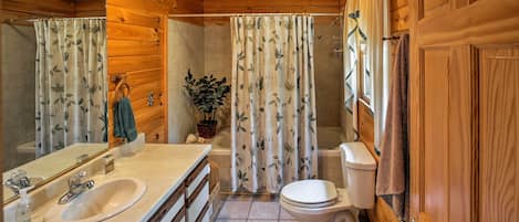 Une salle de bain rustique, aménagée dans une cabane en bois, avec un lavabo, des toilettes et une douche.