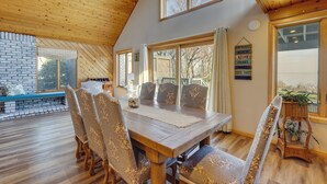 A dining area with a wooden table and chairs, large windows, and a view of the outdoors. - Amazing Rocky Point Retreat Overlooking the Sound! (Rocky Point)