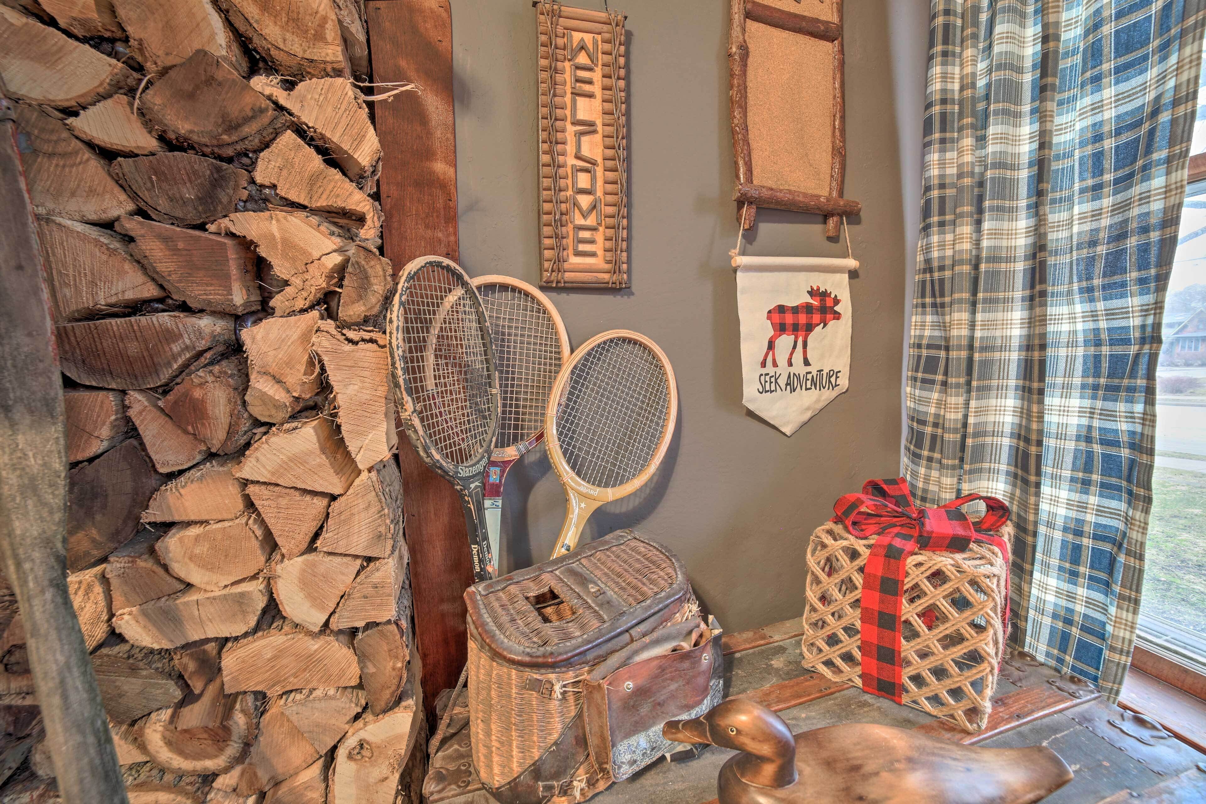 A rustic room with a stone wall, two tennis rackets, a wicker basket, a wooden duck, and a plaid curtain.
