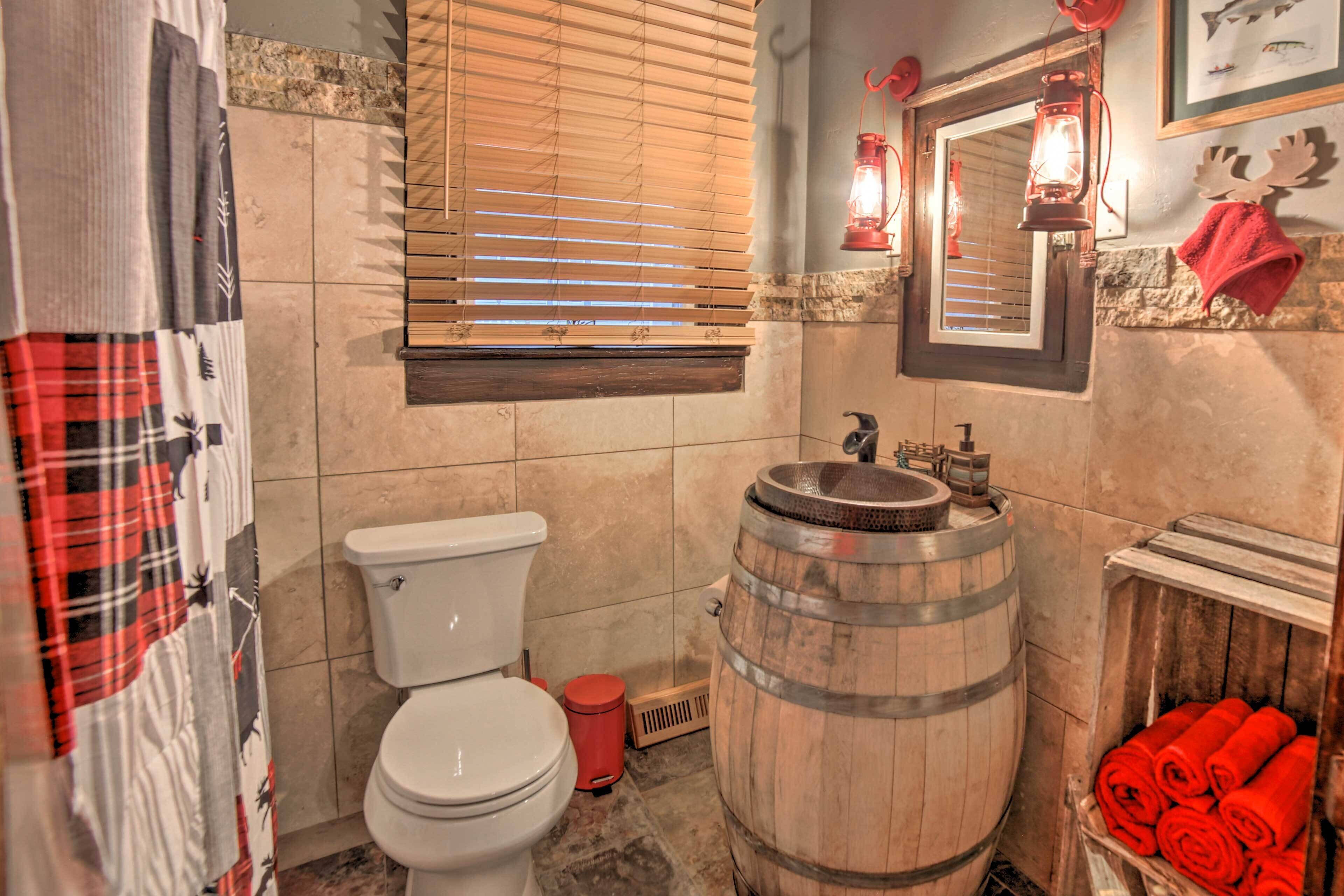 Ein Badezimmer mit Toilette, Holzfass und rotem Handtuchhalter.
