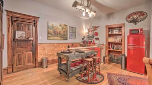 A rustic kitchen with wooden cabinetry, a red refrigerator, and a bar area with stools. - Walk to Waterfront: Dtwn Sturgeon Bay Retreat! (Sturgeon Bay)