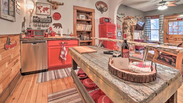 A rustic kitchen with wooden cabinets, a red refrigerator, and a wooden dining table. - Walk to Waterfront: Dtwn Sturgeon Bay Retreat! (Sturgeon Bay)