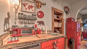 A kitchen with a red refrigerator, a stove, and a microwave. There are shelves with jars and mugs, and a bear silhouette on the wall. - Walk to Waterfront: Dtwn Sturgeon Bay Retreat! (Sturgeon Bay)