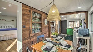 A dining area with a wooden table set for four, a hanging light fixture, and a kitchen in the background. - Stoney Creek Cottage: Waterfront Hot Tub, Fire Pit (Nellysford)