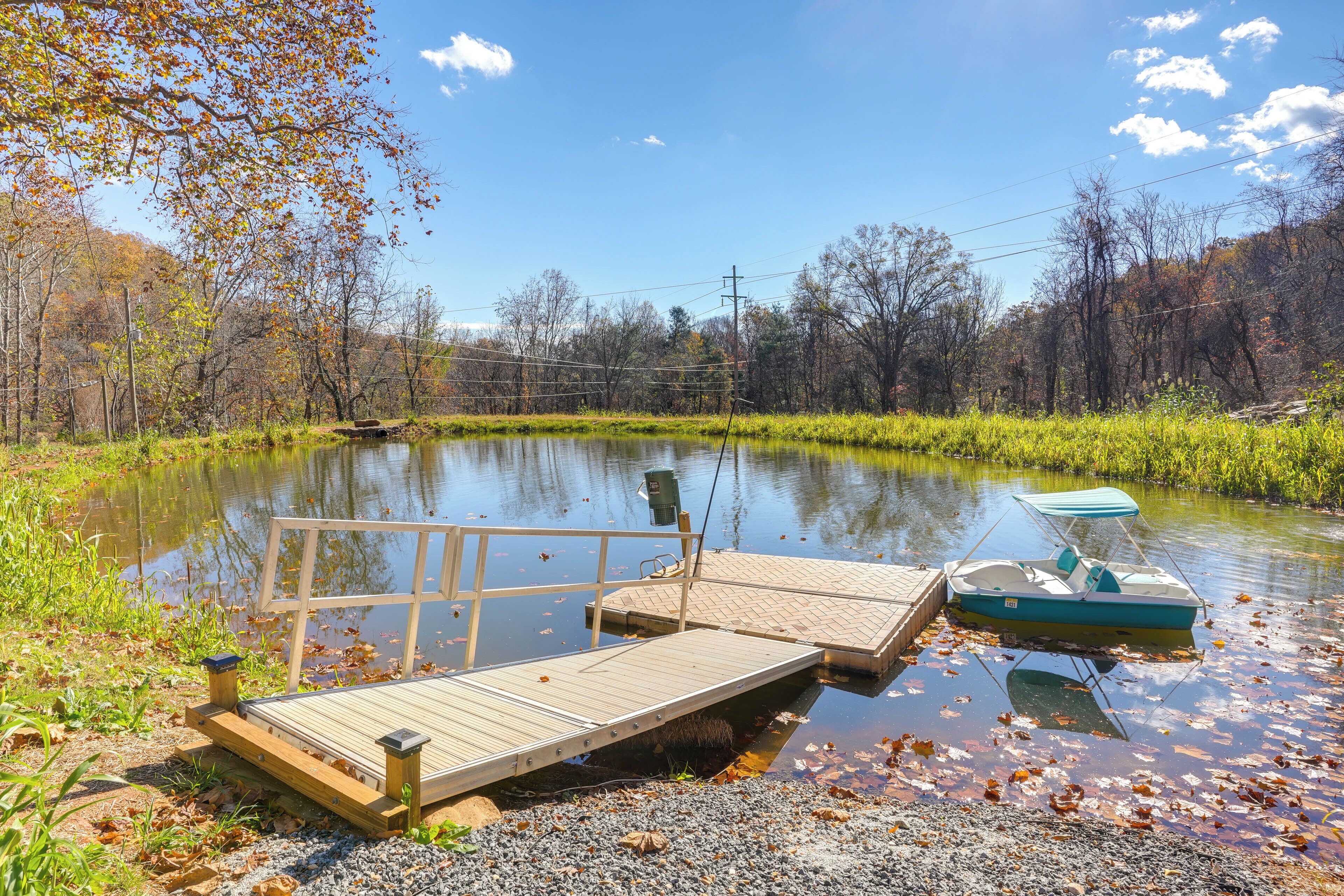 A wooden dock extending into a calm body of water with a small boat docked nearby.