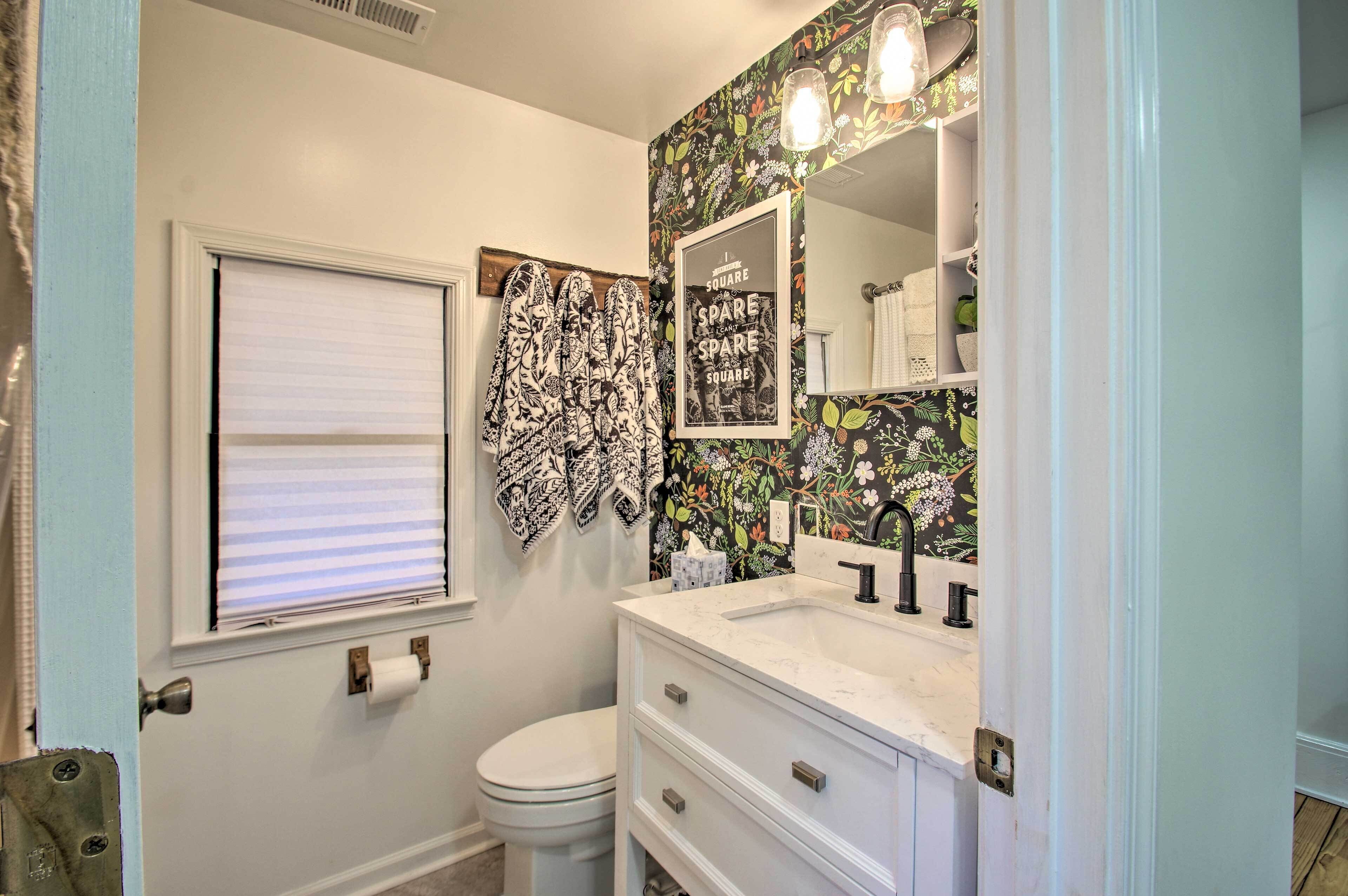 A bathroom with a toilet, a sink with a mirror, and a window with blinds.