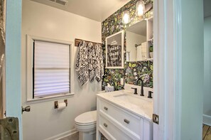 A bathroom with a toilet, a sink with a mirror, and a window with blinds. - Stoney Creek Cottage: Waterfront Hot Tub, Fire Pit (Nellysford)