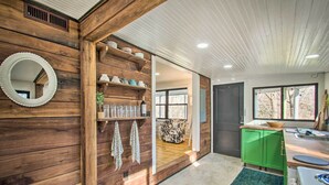 A kitchen with wooden walls, a green cabinet, and a large window. - Stoney Creek Cottage: Waterfront Hot Tub, Fire Pit (Nellysford)