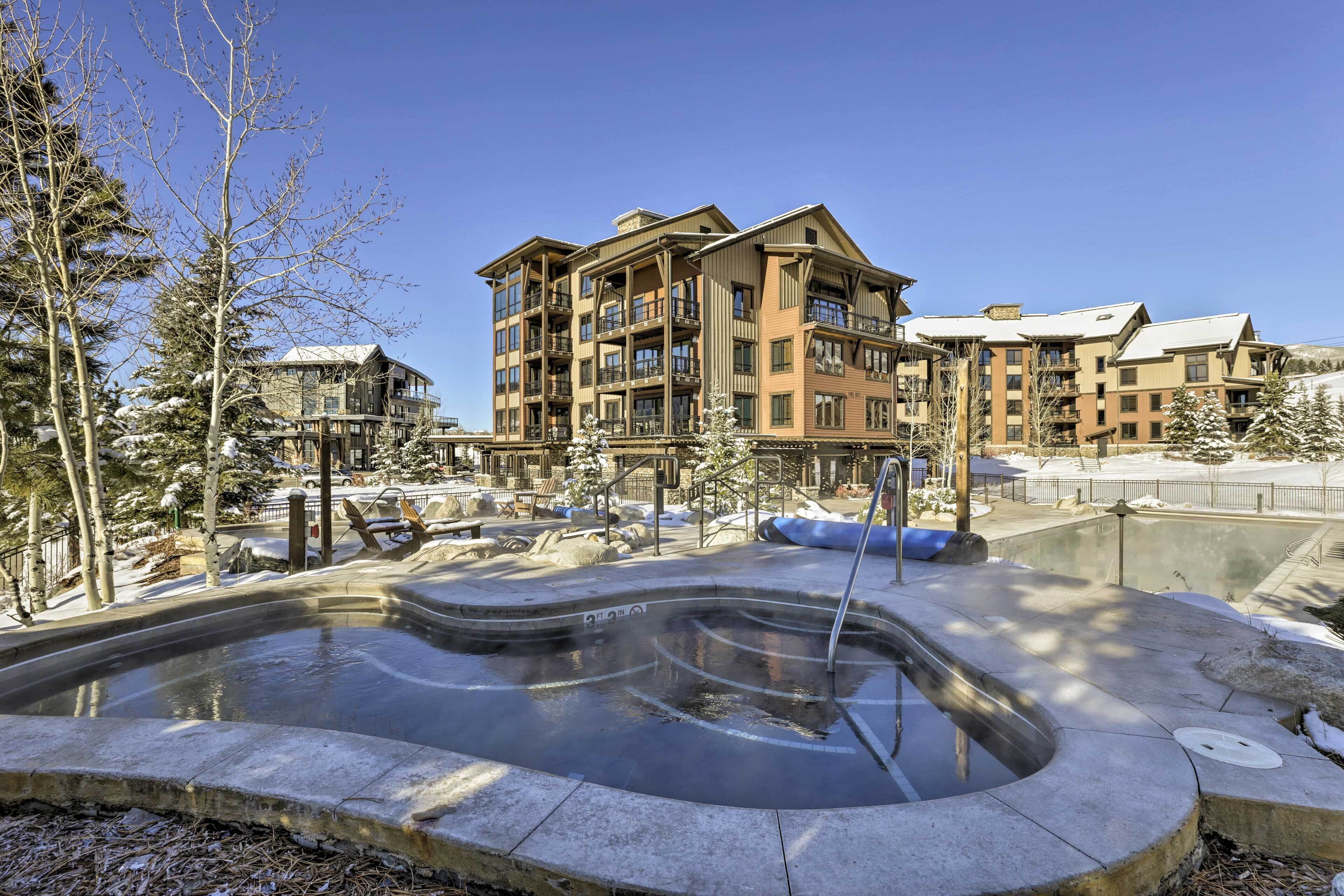A multi-story hotel with balconies, a swimming pool, and snow-covered trees.