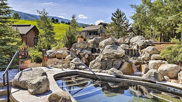 A pool with a waterfall feature, surrounded by large rocks and a wooden deck. - Wildhorse Meadows Studio w/ Resort Gondola Access! (Steamboat Springs)