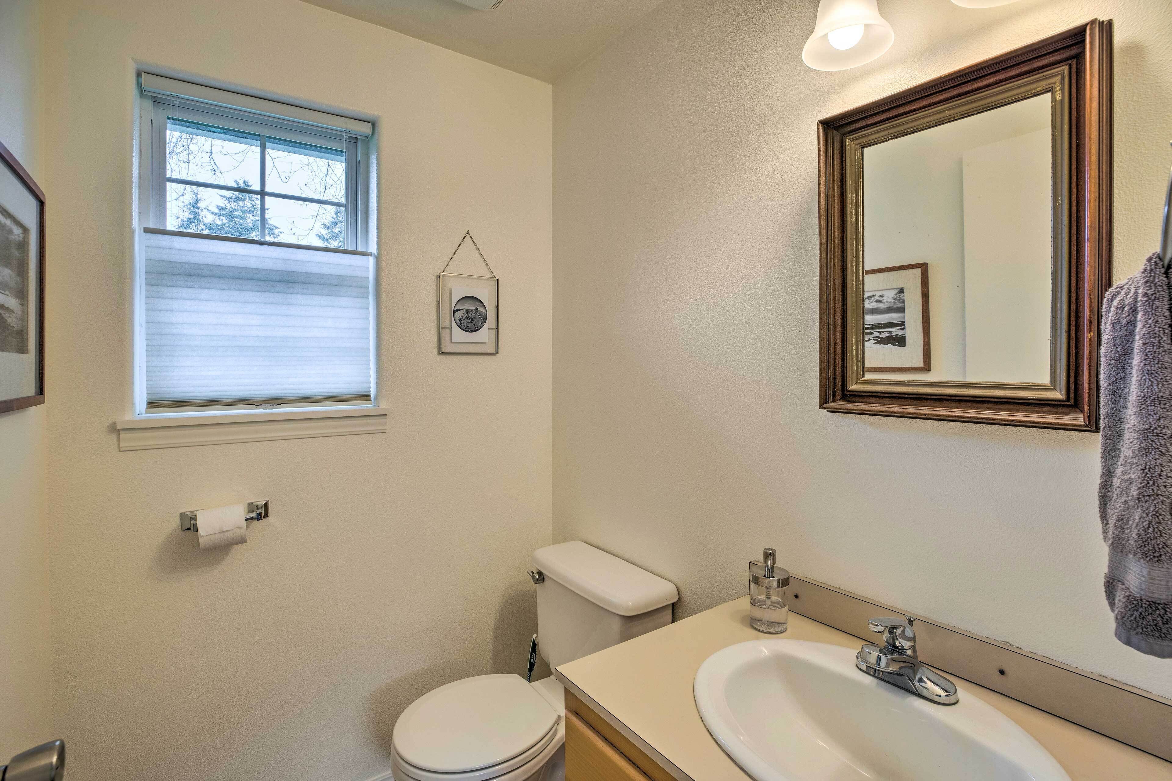 A bathroom with a toilet, sink, and window.